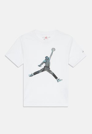 Άσπρη βαμβακερή μπλούζα t-shirt με γραφικό σχέδιο που απεικονίζει μια αναπηδούσα φιγούρα σε μαύρο με μπλε λεπτομέρειες, φορώντας παπούτσια και κρατώντας ένα μπάσκετ.