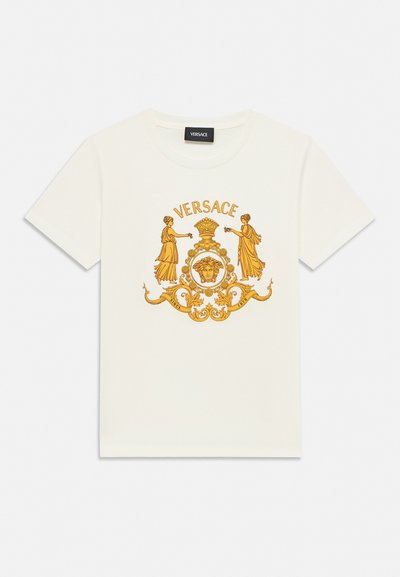 T-shirt blanc à manches courtes avec un motif classique doré représentant deux femmes en toge, un emblème couronné et le texte « VERSACE » au-dessus.