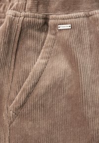 Bruine Corduroy broek met verticale ribbels, zijzak en een klein merklabel met de tekst "Street One." Zachte textuur en casual ontwerp.