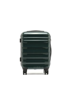 Hardshell suitcase in dark green, featuring a glossy finish, vertical ridges, black hardware, and dual wheels for mobility.