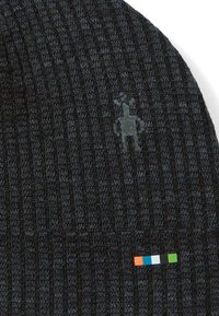 Neulottu tummanharmaa pipo, jossa on pystysuorat tekstuuriraidat, vaalea logo, ja pieni monivärinen merkki alareunassa.