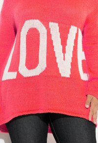 Helles, rosa gestricktes Sweatshirt mit großen weißen Buchstaben, die "LIEBE" buchstabieren. Lockere Passform mit einem gerippten Kragen und Bündchen.