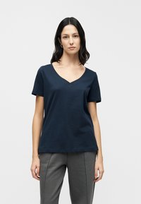 Μπλε σκούρο μπλουζάκι με κοντό μανίκι και σχέδιο V-λαιμού. Κατασκευασμένο από μαλακό ύφασμα με άνετη εφαρμογή και ελάχιστες ραφές.