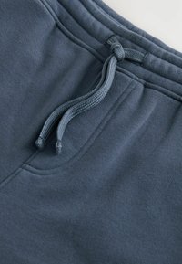 Pantalones de chándal azul oscuro con una suave mezcla de algodón, cinturilla elástica y cordón para un ajuste ajustable. Sin patrones ni herrajes visibles.