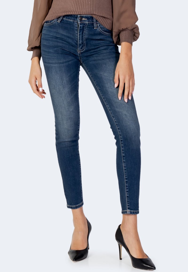 Tunna blå jeans i denim, med en medelhög midja, subtila slitageeffekter och en figurnära silhuett. I kombination med svarta stilettklackar.