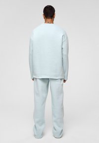 Lichtblauwe oversized sweatshirt en bijpassende sweatpants, gemaakt van zacht materiaal, met een relaxte fit en minimale stikseldetails.