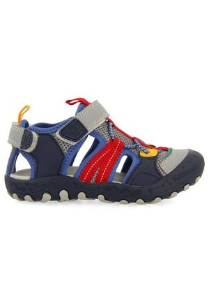 Sandalia en azul marino y gris con laterales de malla, cordones elásticos de colores y suela de goma texturizada con un patrón de agarre. Cierre con correa ajustable.