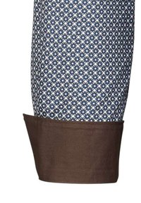 Manica di camicia in cotone con un motivo geometrico blu e bianco, polsino marrone, texture liscia e forma sagomata.