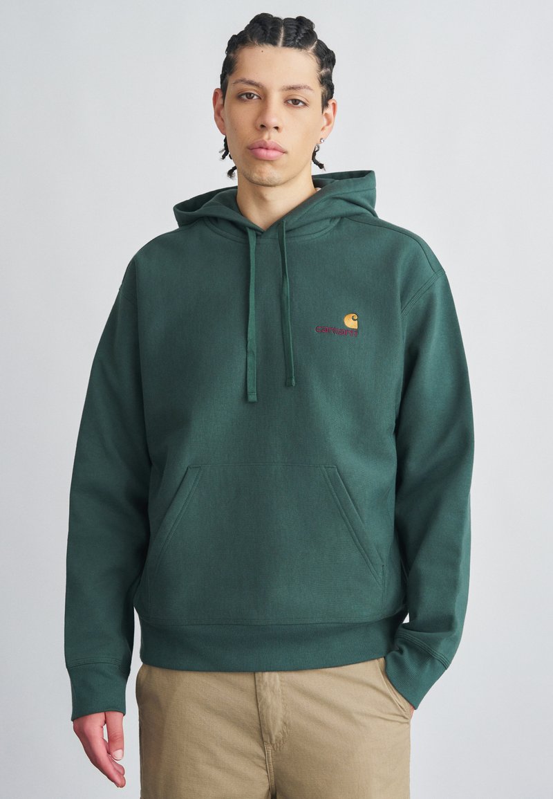 Sudadera con capucha de color verde oscuro hecha de tela suave, con un gran bolsillo frontal, cordones y un pequeño logo bordado en el pecho.