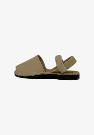 Sandal in pelle beige con suola piatta, design aperto e cinturino alla caviglia regolabile. Presenta cuciture a contrasto lungo i bordi.