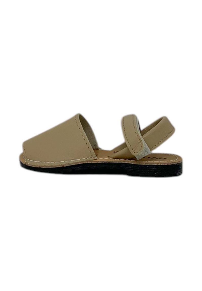 Sandal in pelle beige con suola piatta, design aperto e cinturino alla caviglia regolabile. Presenta cuciture a contrasto lungo i bordi.