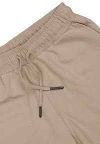 Beżowe spodnie dresowe z prążkowanej tkaniny, z elastycznym paskiem w talii, z regulowanym sznurkiem z czarnymi końcami. Gładka tekstura i luźny krój.