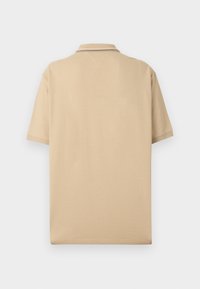 Polo beige con maniche corte, dotato di un colletto bicolore e una vestibilità rilassata. Realizzato in morbido cotone.