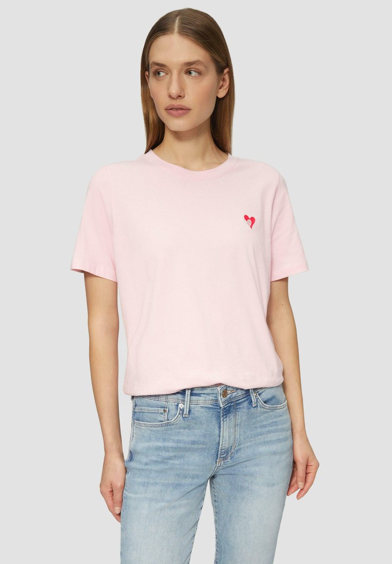 Lichtroze katoenen t-shirt met korte mouwen en een ronde halslijn, met een klein rood hartontwerp op de linkerkant van de borst.