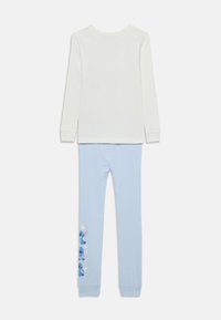 Haut à manches longues blanc associé à des leggings bleu clair avec un imprimé du personnage Stitch et des étoiles le long d'un côté.