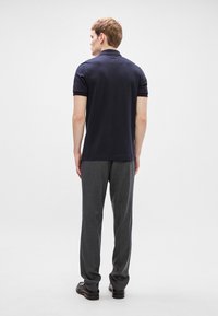 Ναυτική πόλο μπλούζα με κοντά μανίκια, σε συνδυασμό με γκρι εφαρμοστά παντελόνια. Το σύνολο διαθέτει λεία υφή και κλασική εφαρμογή με ελάχιστες λεπτομέρειες.