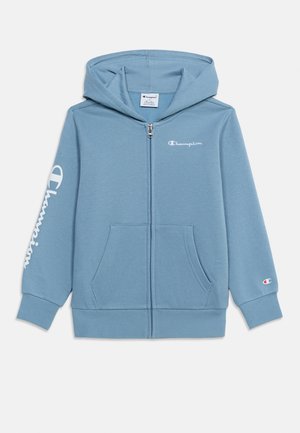 Jasnoniebieska bluza z kapturem i zamkiem błyskawicznym, z przednimi kieszeniami, logo Champion na piersi, lewym rękawie i prawym mankiecie oraz kapturem.