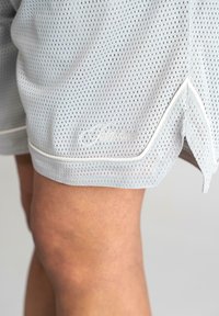 Light gray mesh athletic shorts with a textured pattern, featuring white piping along the hem and a branded logo on the leg.