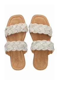 Twee platte sandalen hebben brede, gevlochten banden versierd met metalen rhinestones. De voetbed is gemaakt van tan suede met een gestikte rand.