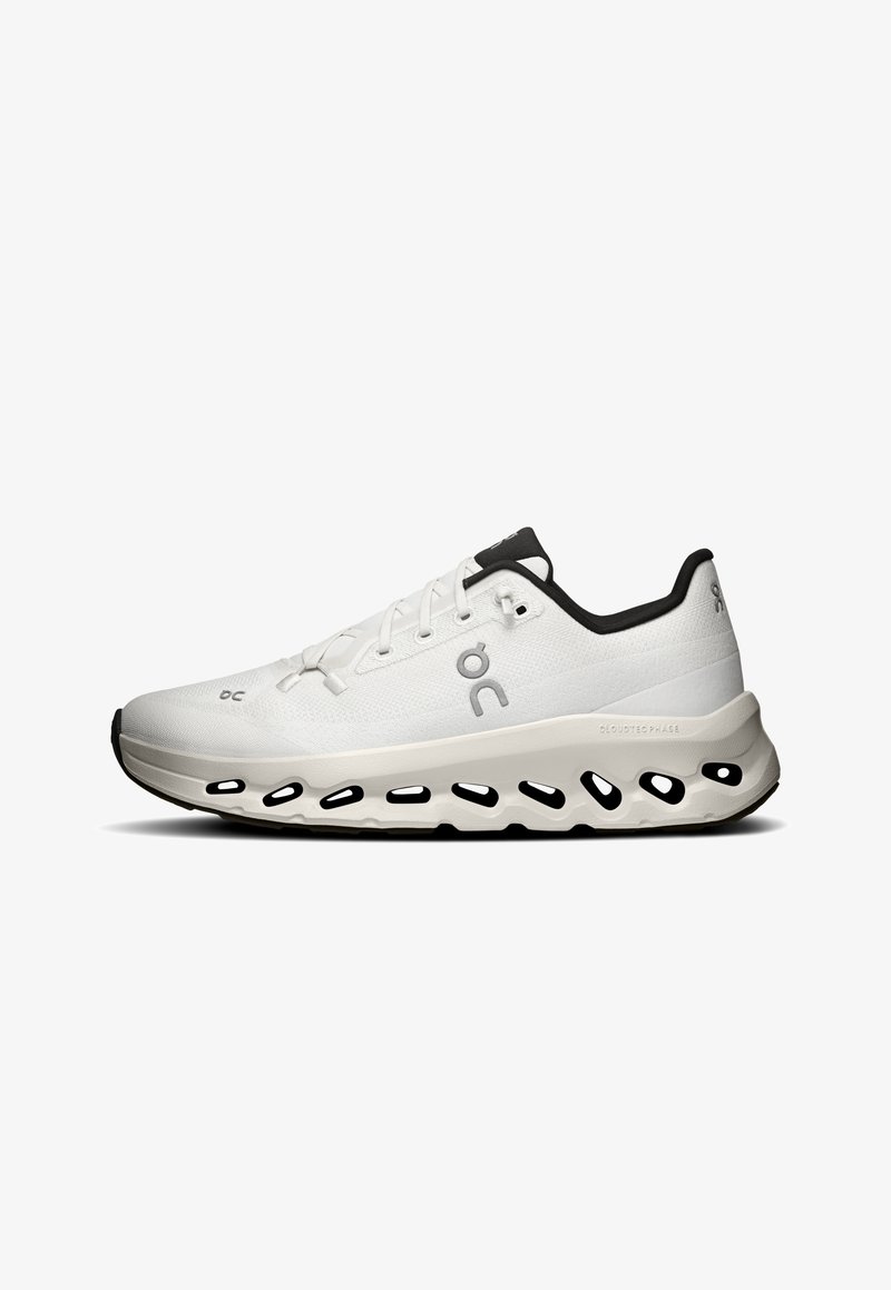 Scarpa sportiva bianca con una parte superiore texturizzata, accenti neri e una suola imbottita con pod di ammortizzazione esposti. Lacci e design minimalista.