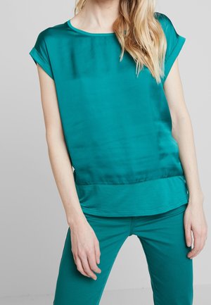 Haut court en satin bleu sarcelle à manches courtes avec un col rond, présentant une texture lisse et une coupe légèrement évasée à l'ourlet.