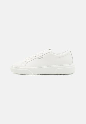 Biały niski sneaker z sznurowadłami i grubą podeszwą, widok z boku, pokazujący tekst "CPHGN" na zewnętrznej stronie.