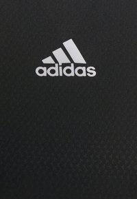 Czarna tkanina z teksturowanym wzorem; na środku znajduje się wyraźne białe logo Adidasa.