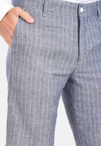 Pantaloni in lino leggeri di colore grigio-blu, con sottili righe bianche, tasche laterali e chiusura con bottone.