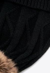 Czarna dziergana czapka z teksturowanym wzorem i ozdobnym pomponem z futerka syntetycznego. Materiał jest miękki, z widocznymi detalami prążkowanego ściegu.