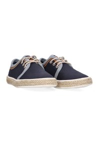 Zapatos de lona azul marino con acentos grises, cordones beige y suela de cuerda de yute. Presentan una puntera redondeada y detalles de costura en contraste.