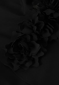 Fekete anyag, háromdimenziós, rétegezett szirmokból készült virágdíszítésekkel, sima textúrával és elegáns, folyékony formával.