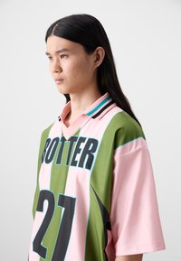 Colorful oversized polo shirt featuring horizontal green and pink stripes, with the word "BOTTER" and the number "21" in bold black print.