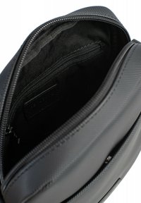 Borsa nera in nylon con una texture liscia, chiusura con zip e una tasca interna. Presenta un'etichetta del marchio discreta all'interno.