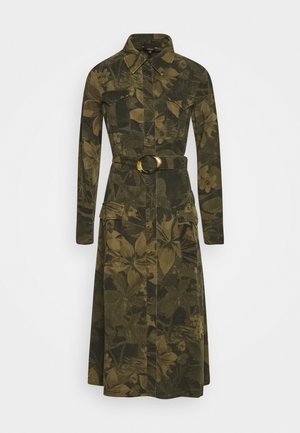 Robe chemise manches longues à motif camouflage floral vert et marron, boutonnage devant, poches poitrine, ceinture avec boucle ronde et poches à rabat sur les cuisses.