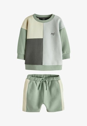 Dvojdielny set obsahujúci top s dlhým rukávom a šortky. Mäkká bavlnená tkanina v mätovo zelenej farbe s béžovými a sivými obdĺžnikmi a malým logom.