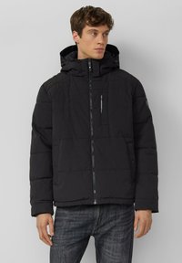 Zwarte gewatteerde jas met capuchon, ritssluiting aan de voorkant en zijzakken. Heeft een subtiele structuur en een strak, modern design.