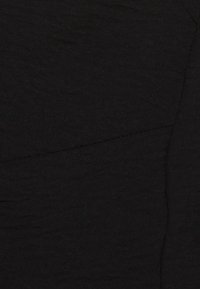 Tissu noir avec une finition texturée, présentant des coutures subtiles et un léger éclat. Le matériau semble lisse et dense, sans motifs visibles.