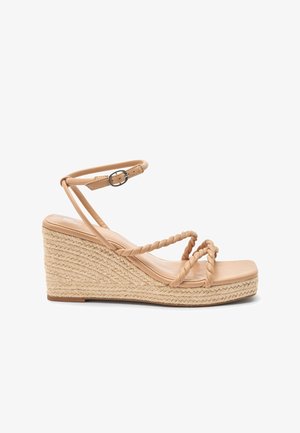 Beżowe sandały na koturnie z plecionymi paskami, zapięciem na kostkę i podeszewką obszytą jutą. Gładka tekstura i minimalistyczny design.