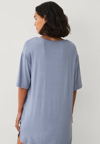 Løs pasform, kortærmet T-shirt i lyseblåt stof. Har en rund halsudskæring og sideslids, med en glat og blød tekstur.