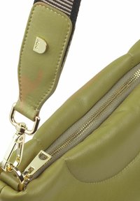 Borsa in pelle verde oliva con accessori dorati, dotata di chiusura a zip e di una tracolla a righe in contrasto con un accento dorato sulla sezione regolabile.