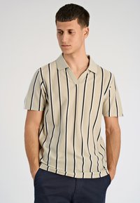 Beżowy polo z krótkim rękawem w niebieskie pionowe paski, z kołnierzykiem typu V i miękką, teksturowaną tkaniną.