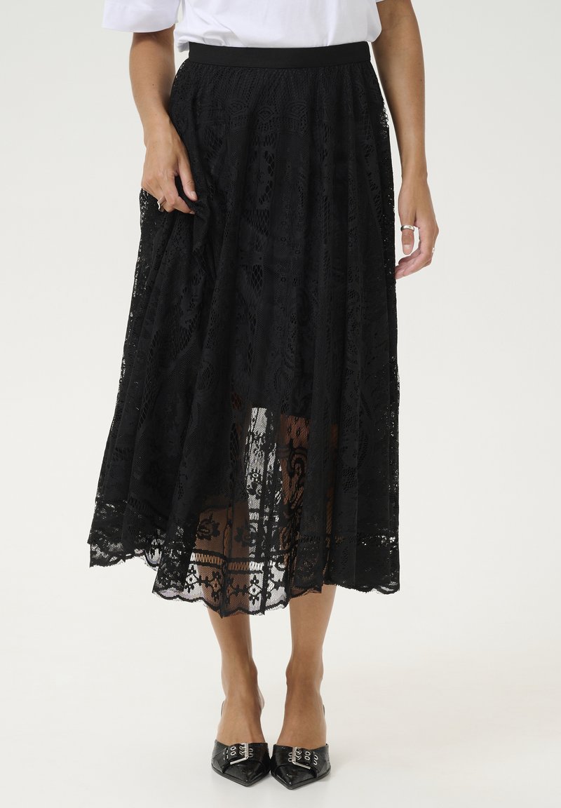 Gonna maxi nera in pizzo con un design a strati trasparente, modelli testurizzati e una vita aderente. Abbinata a scarpe nere a punta.