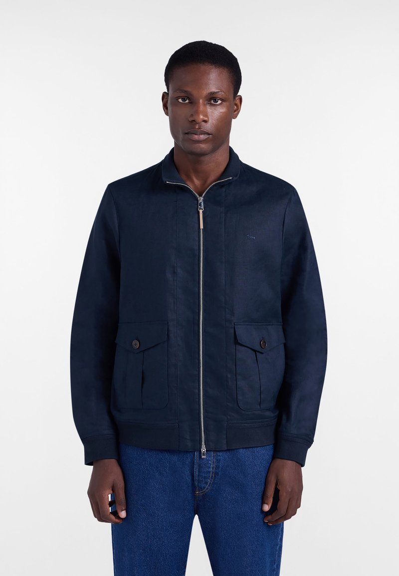 Navy blue jacket made of textured fabric, featuring a front zipper, ribbed cuffs, two flap pockets, and a subtle logo detail.