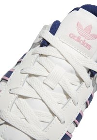 Bijele kožne tenisice s mornarsko plavim i ružičastim detaljima, sa bijelim vezicama, teksturiranim detaljima na gornjem dijelu i ružičastim logotipom na jeziku.