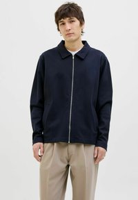 Jūrinės tamsiai mėlynos zip-up striukės su apykakle, ilgomis rankovėmis ir šoninėmis kišenėmis. Pagaminta iš minkštos medžiagos su lygiu paviršiumi.