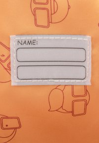 Narancsszínű textil, ismétlődő kontúrmintával. A tetején egy fehér névcímke található, két üres sorral a nevek számára.