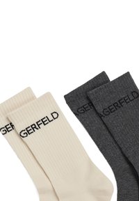 Calzini di cotone in beige chiaro e grigio scuro, con texture a costine e il logo nero "GERFELD" in evidenza.