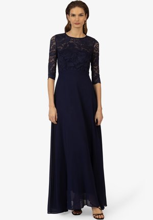 Abito da sera blu navy con maniche in pizzo a tre quarti, corpetto in pizzo floreale, gonna fluida e vita definita. Il materiale sembra morbido con una finitura lucida.