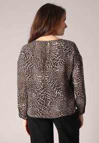 Blouse à imprimé léopard en tissu léger, dotée de manches longues, d'un col rond avec une ouverture en forme de clé à l'arrière et d'une coupe décontractée.