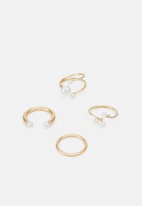 Quattro anelli realizzati in metallo color oro, due dei quali con perle bianche. Un anello ha una semplice fascia, mentre un altro presenta un design a spirale con perle.